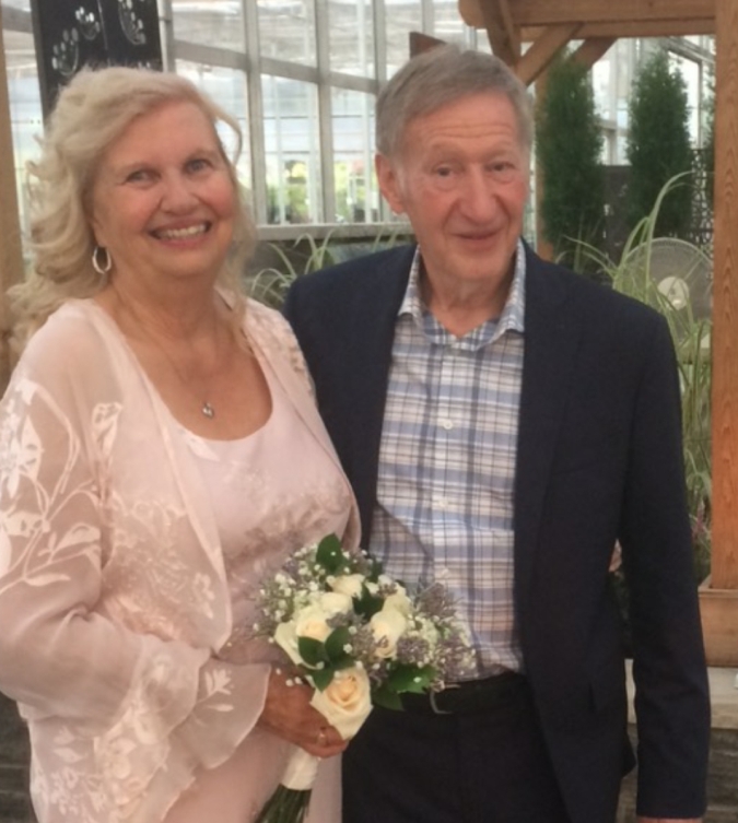 A beautiful mature Christian woman smiles next to her husband while holding her bouquet