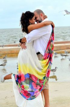 A Beautiful Christian single woman jumps up as a man kisses her on a beach