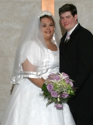 Born again Christian bride holds beautiful bridal flowers as she smiles joyfully next to her husband