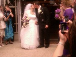 Recently married Christian couple kiss as they enter the reception room