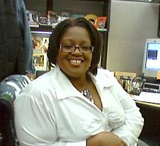 A woman with a beautiful smile sits at a computer desk