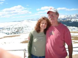 Mature Christian single is hugged by a man at a mountain lookout