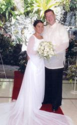 American man poses next to his Filipina bride who holds flowers