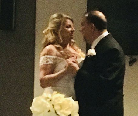 A bride gazes into her new husband's eyes as they dance closely at their wedding