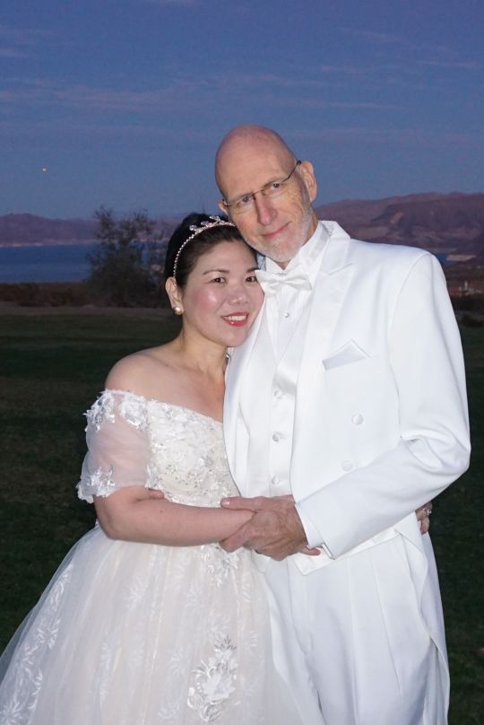 Interracial couple holding each other after outdoor wedding