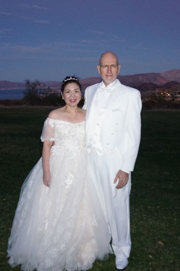 Sunset wedding on beautiful grass for bride and groom both dressed in white