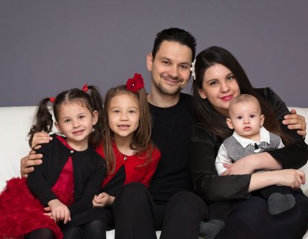 Very proud Christian dad with his beautiful wife poses with their 3 children