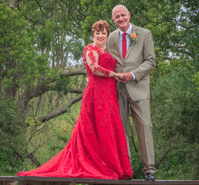 Proud bride laughs at joke while husband leans in