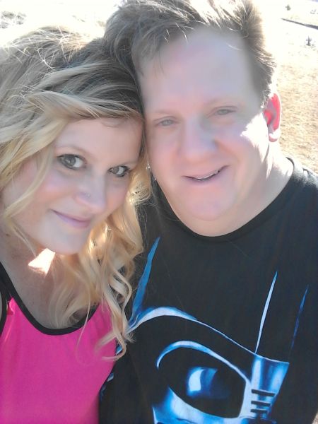 Christian singles made for each other smile at camera. Her in pink top and blonde hair, him in black Darth Vader shirt and windblown blonde hair