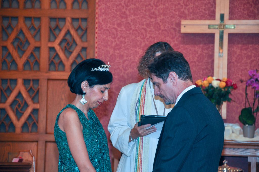 An Asian bride prays with her White husband at their church wedding