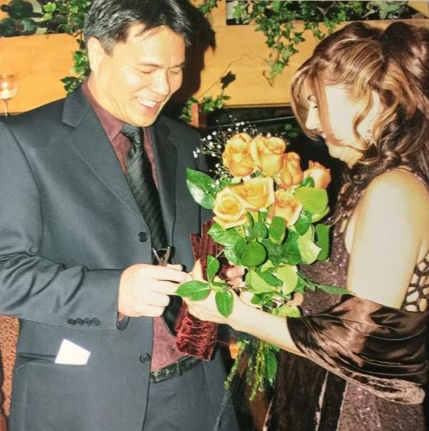 Putting on the wedding ring on his bride, with bouquet in foreground