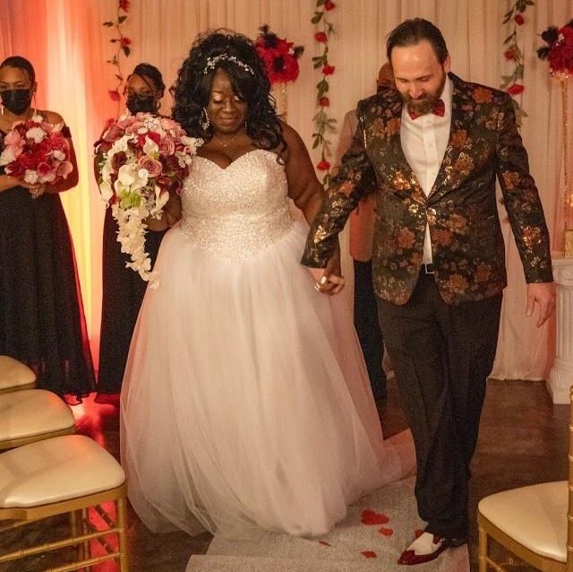Newlyweds pray together while holding hands at an indoor wedding during COVID