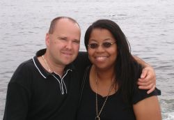 A couple very much at ease with each other embrace by the water