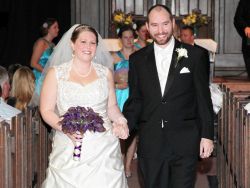 A beautiful bride walks hand in hand with her new husband as churchgoers look at them