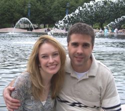 A man hugs a beautiful woman in front of a fountain