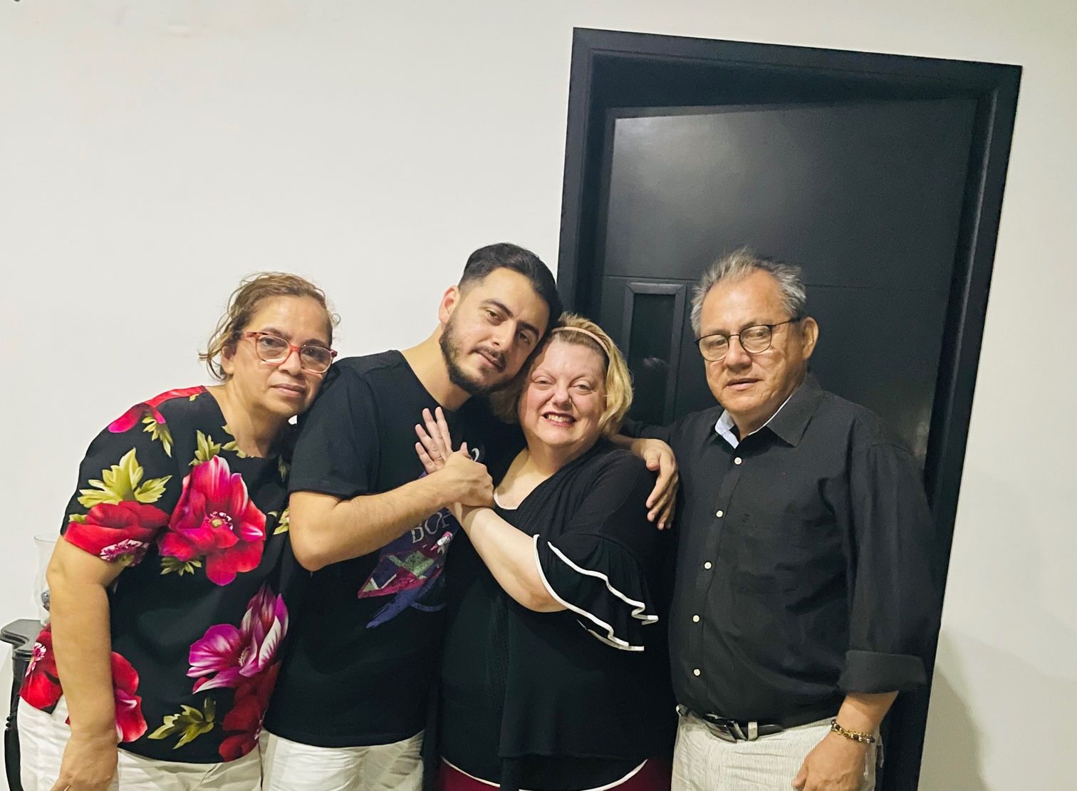A newly engaged Christian couple cuddle next to his parents, while the woman displays her engagement ring and a huge smile