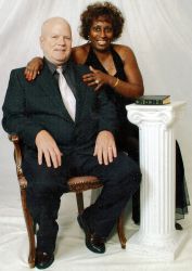 A very happy interracial couple pose while seated