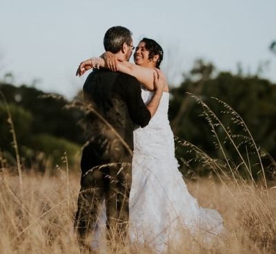 Happy Christian bride laughing while putting arms around husband and smiling