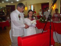 A groom and bride, both in white stand together at their wedding ceremony