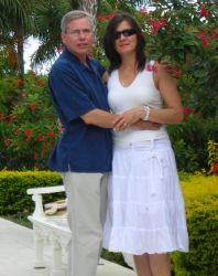 A couple pose together arm in arm in a beautiful garden