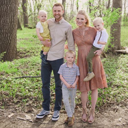 Christian couple standing in forest while holding their 3 children
