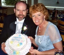 Cross state romance for Christian singles leads to marriage. Man and woman smile as they hold up a unique round wedding cake
