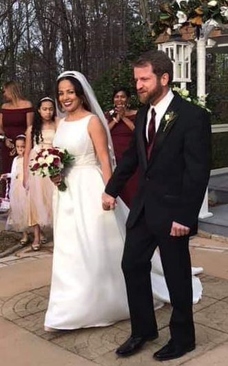 Newly Married Christian couple holding hands while walking down the aisle
