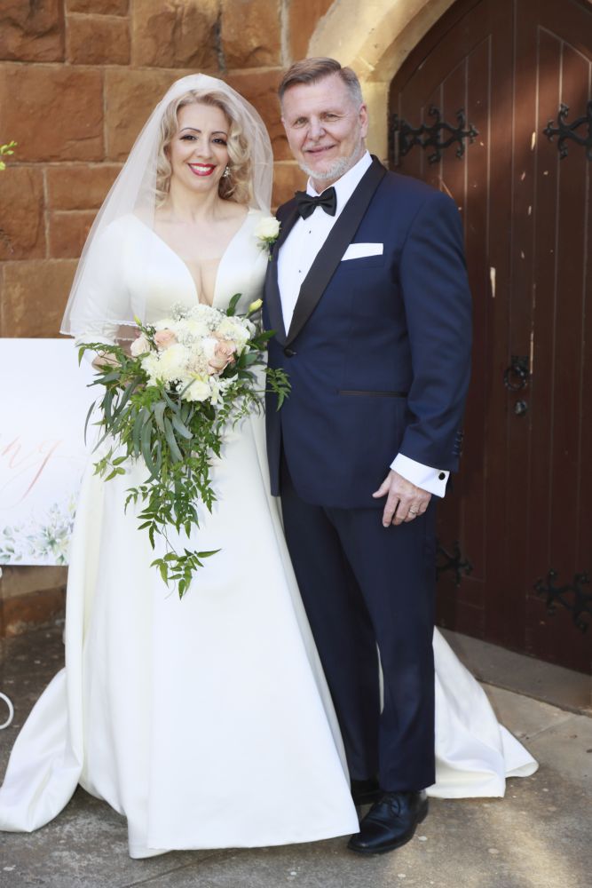 Christian bride in a stunning dress holds flowers while standing next to her new husband