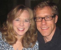 A woman breaks out in laughter as she poses with a man in glasses