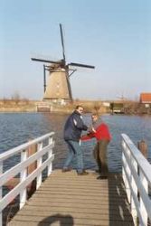 A man pretends to jump off a dock while his wife pretends to hold him back