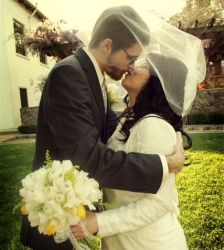 A Christian couple kiss lovingly on their wedding day under her veil
