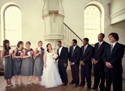 A bride and groom nearly doubled over laughing while the bridal party joins poses and laughs too