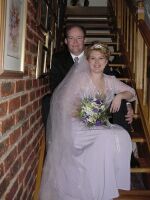 Beautiful wedding cress and veil on display as happy bride and groom pose together on the stairs