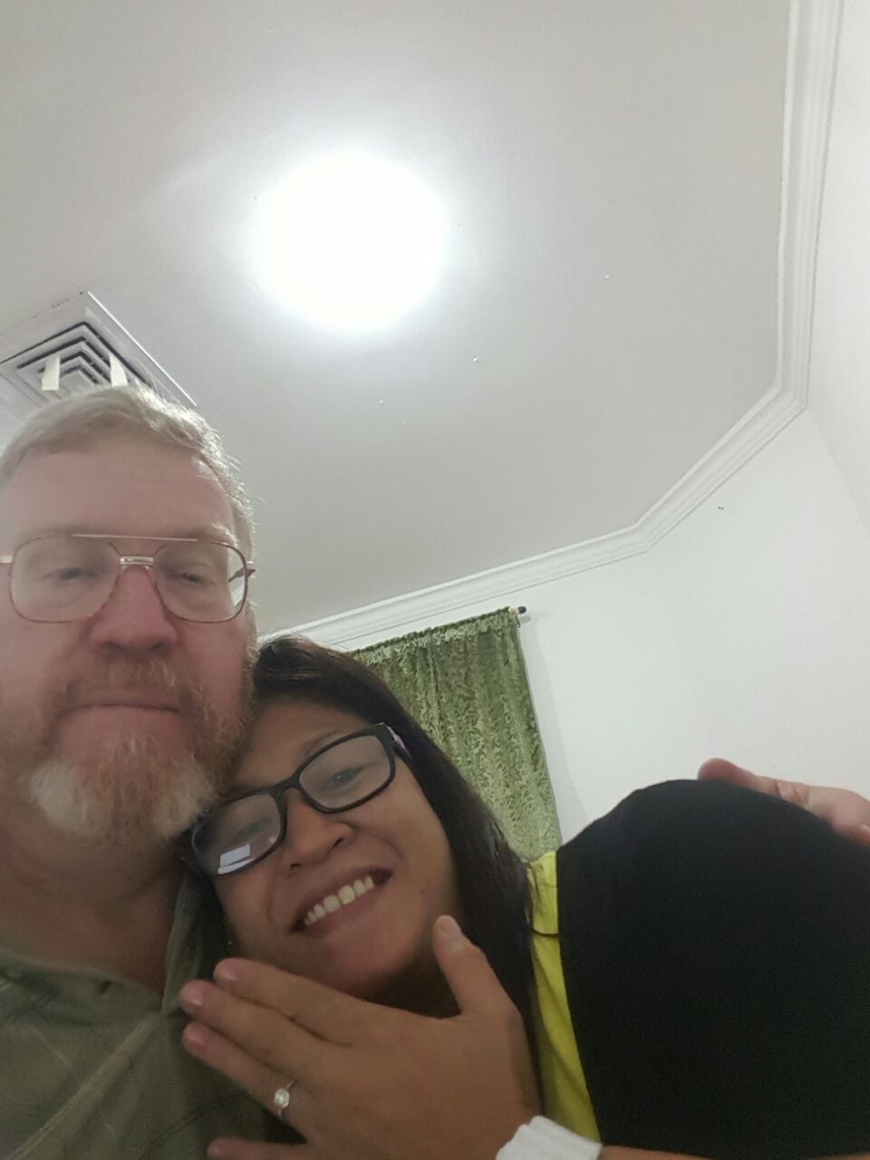 A woman smiles while hugging her fiance and showing off her engagement ring on video
