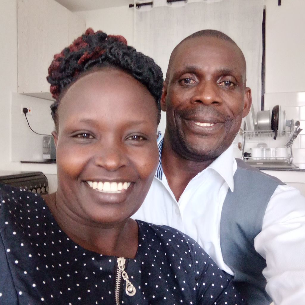 A beautiful Christian woman smiles as her husband stands behind her in the kitchen