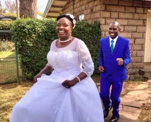 A groom dances out of the church in his blue suit while his beautiful bride walks ahead, laughing