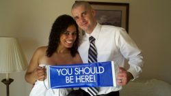 Newlyweds hold up a sign for Christian singles which reads You Should Be Here!