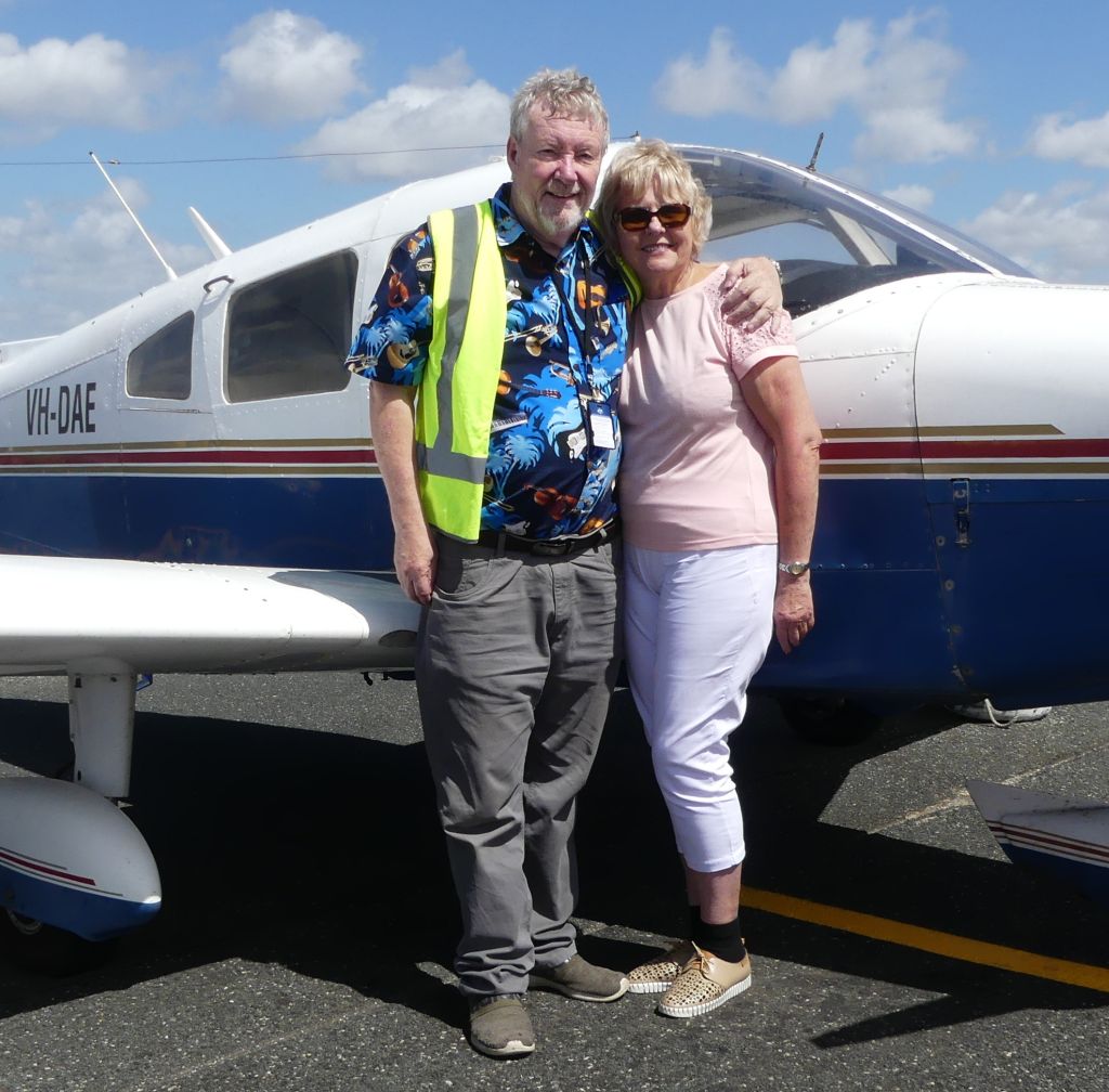 A very happy single Christian pilot from Western Australia poses with his date in front of a small plane