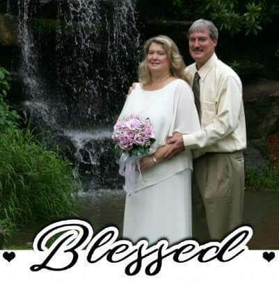 Middle aged couple smiling next to waterfall while hugging