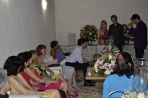 Surrounded by wedding guests who are seated, a newly married couple give their wedding speech