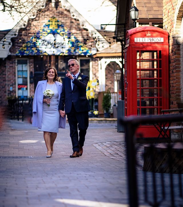 A groom holds his bride's hand while walking in London