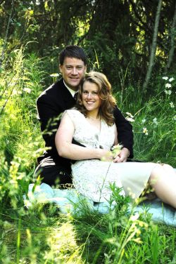 A beautiful Christian single from Idaho sits on the grass and leans into a man's arms