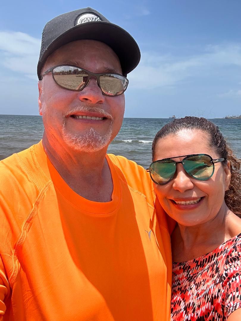 An older Christian couple smile in the sunshine in front of the seaside in Honduras