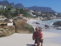A man kneels down on the sand with his daughter while at the beach