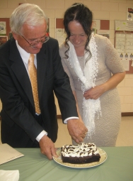 A man cuts a piece of cake for a beautiful woman