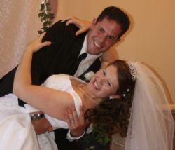 A loving husband leans his new wife over to kiss her as she laughs