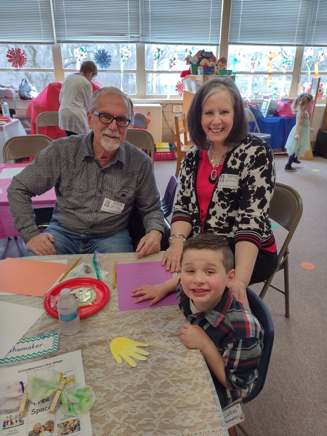 Mature Christian couple sitting a table with their grandson