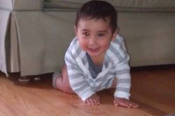 A cute boy laughs while crawling towards the camera