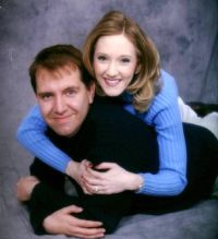 Pretty Christian woman tackles a man by wrapping her arms around him. He smiles.