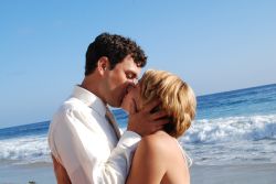 Former California singles lovingly kiss while waves crash on the beach